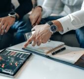 obrazek dekoracyjny przedstawiający dwie osoby, które przedstawiają sobie dokumenty i informacje na tablecie