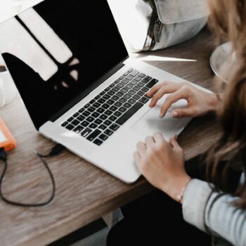 obrazek dekoracyjny -kobieta pracująca na laptopie przy stole