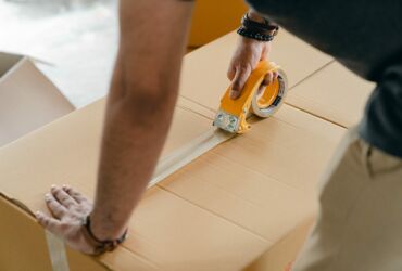 obrazek dekoracyjny przedstawiający osobę zaklejającą paczkę taśmą