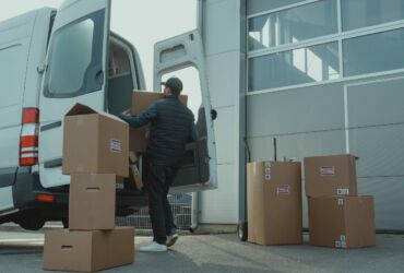 obrazek przedstawiający samochód dostawczy, do którego mężczyzna pakuje duże paczki