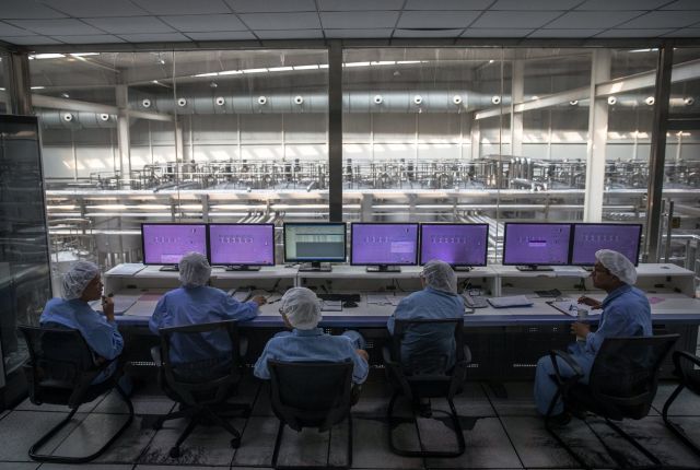 Obrazek przedstawiający grupę ludzi przed ekranami, ubrani są w stroje laboratoryjne