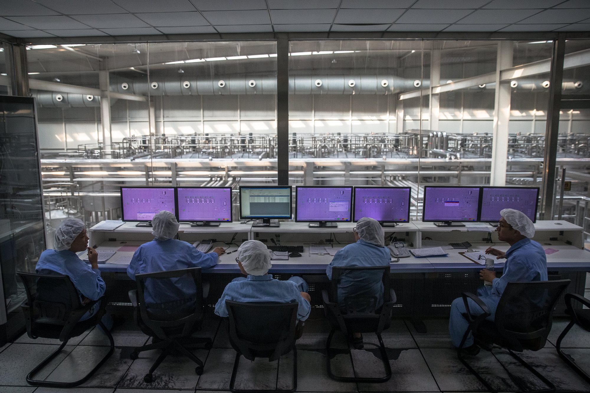 Obrazek przedstawiający grupę ludzi przed ekranami, ubrani są w stroje laboratoryjne