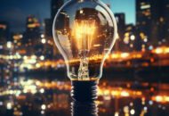 a large glowing light bulb and tall city buildings in the back