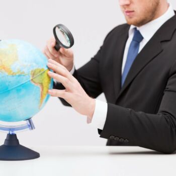 Biznesman patrzy przez lupę na kulę ziemską