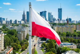 Polska flaga narodowa na tle wieżowców w Warszawie.