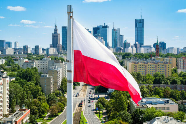 Polska flaga narodowa na tle wieżowców w Warszawie.