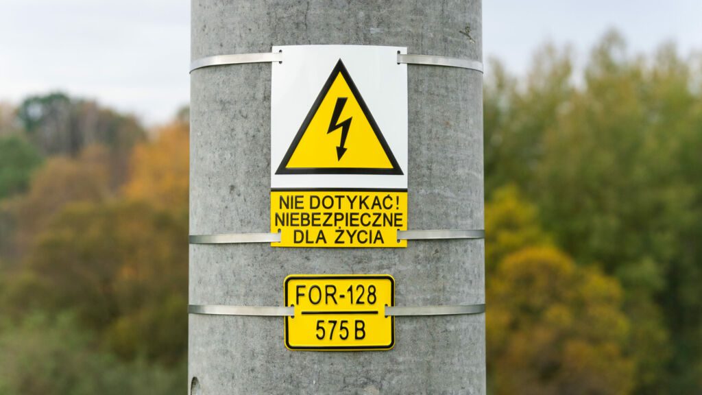 The pole number plate and warning sign are mounted on the pole using stainless steel tape.