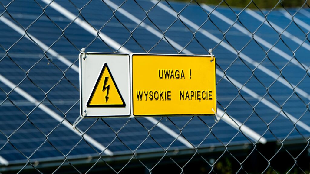 A warning sign mounted on the fence of a solar farm