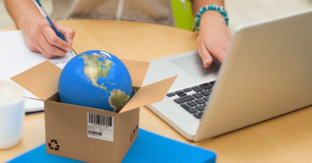 Globe in a box against a background of a woman working on a laptop
