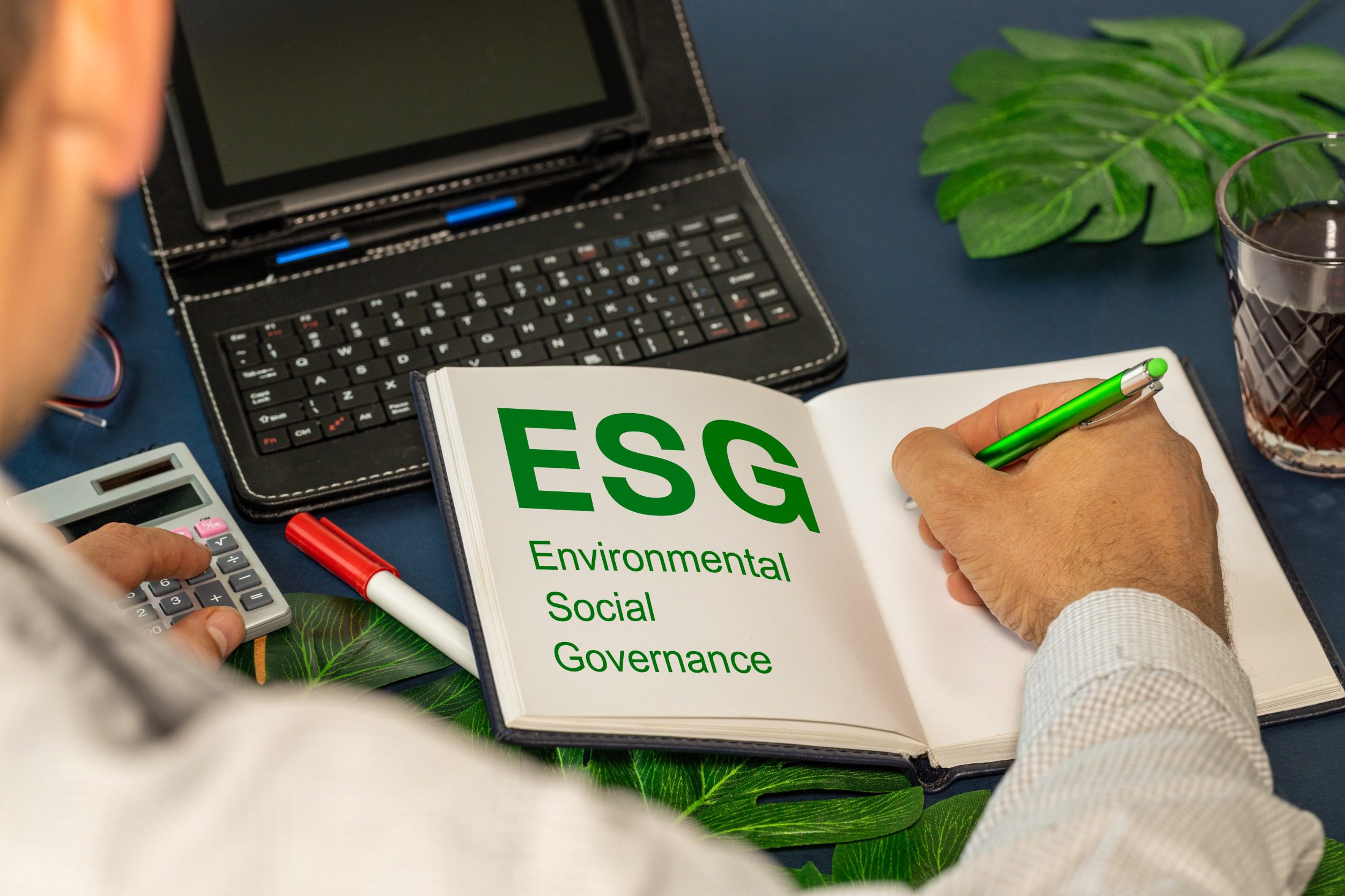Mężczyzna pisze w kalendarzu, gdzie na sąsiedniej stronie widnieje zielony napis ESG