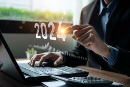 Businessman working on a laptop, the numbers 2024 in the air, which a man clicks on