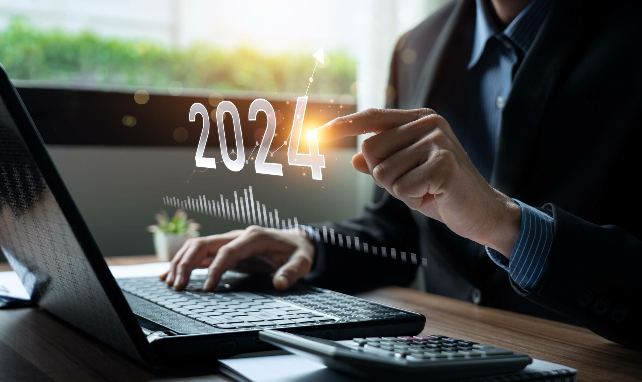 Businessman working on a laptop, the numbers 2024 in the air, which a man clicks on