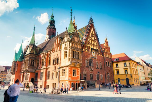 Wrocławski ratusz i rynek o poranku, błękitne niebo i słoneczna pogoda.