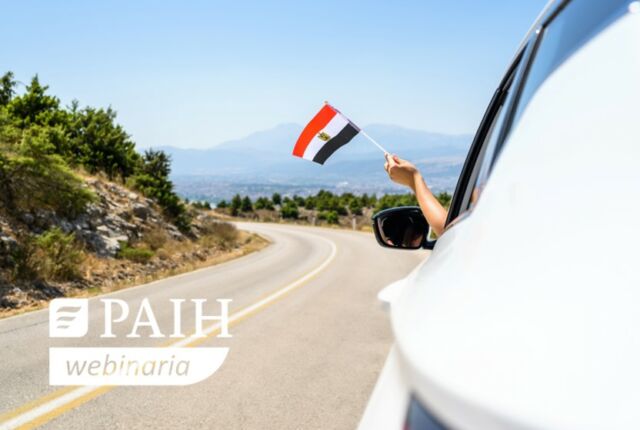 Osoba wyciąga rękę z samochodu z flagą Egiptu