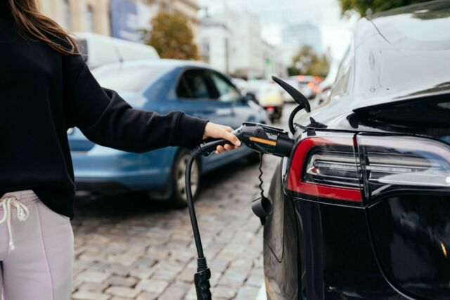 Woman near car. Vehicle charged at the charging station.