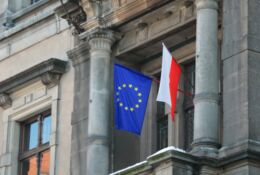 The flag of Poland and the European Union hangs on the building.