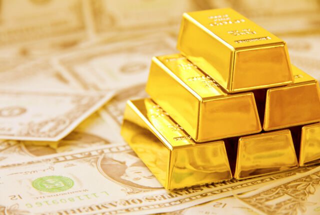 Sztabki złota położone na banknotach dolarów amerykańskich