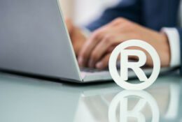 Znak towarowy w pobliżu dłoni mężczyzny pracującego na laptopie