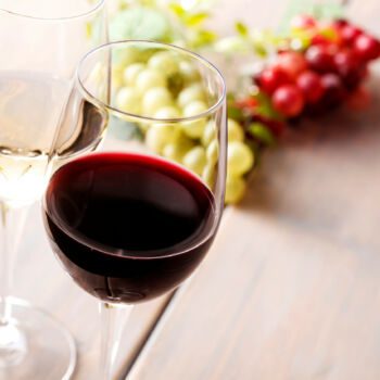 Dwa kieliszki wina, jedno z czerwonym, drugie z białym na drewnianym stole