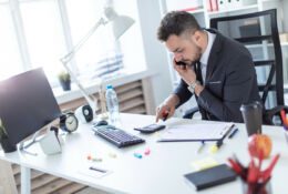 Brodaty mężczyzna w garniturze pracuje przy jasnym biurku
