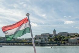Widok zza rzeki na Zamek Królewski w Budapeszcie. Na pierwszym planie powiewająca flaga Węgier