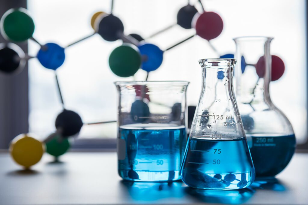 Laboratorium naukowe. Trzy probówki, w tle model struktury cząsteczki,