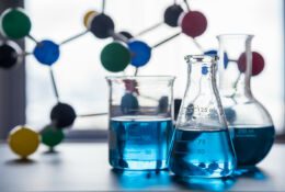 Laboratorium naukowe. Trzy probówki, w tle model struktury cząsteczki,