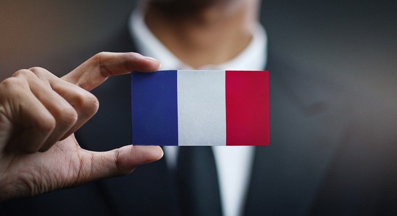 mężczyzna w garniturze trzymający w dłoni flagę Francji