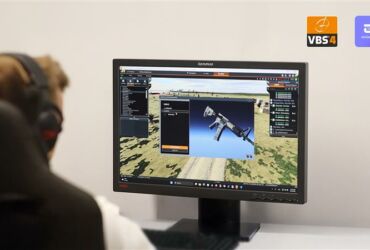 The photo shows a person in front of a monitor displaying a VBS simulation – an image of a weapon and a battlefield