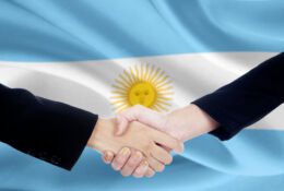uscisk dloni biznesmenow na tle argentynskiej flagi