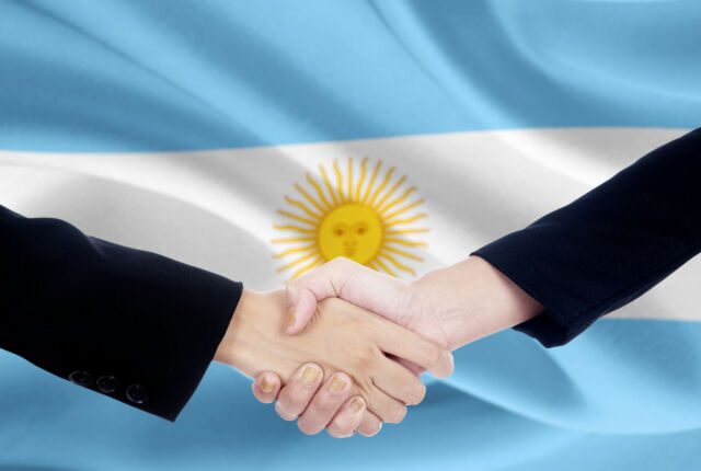 uscisk dloni biznesmenow na tle argentynskiej flagi