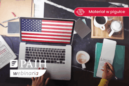 biurko, na nim laptop a na pulpicie flaga USA