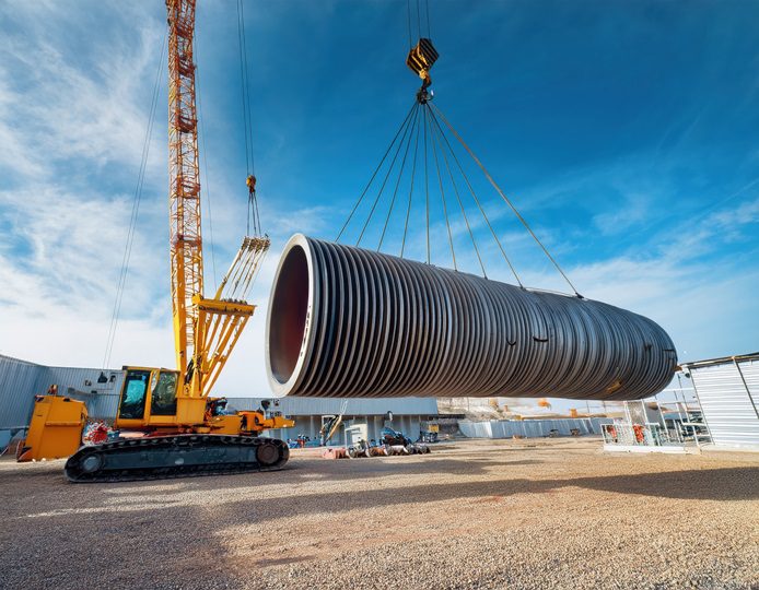 dźwig, ktory unosi fragment rury budowlanej