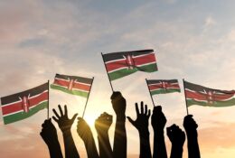 dłonie trzymające małe chorągiewki-flagi Kenii