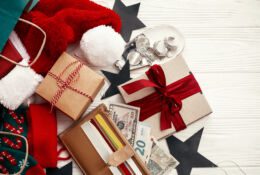 Koncepcja świątecznych zakupów i wyprzedaży. Karty kredytowe i pieniądze w portfelu, papierowe torby z ubraniami, pończochy, pudełka na prezenty i biżuteria na białym, rustykalnym tle.