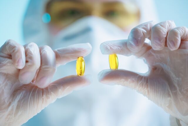 Medyk trzyma żółte kapsułki