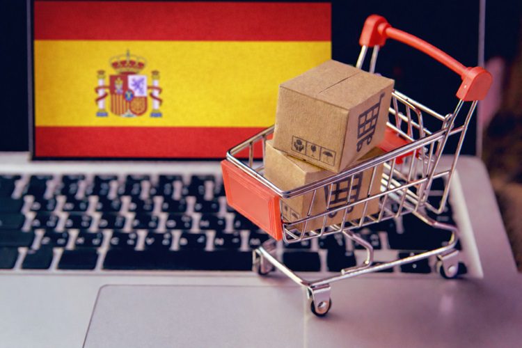 koszyk z zakupami na klawiaturze laptopa i flaga Hiszpanii