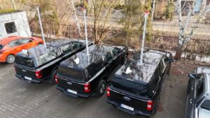 Three operational pickup trucks equipped with specialized modular canopies and telescopic masts, designed for mobile com